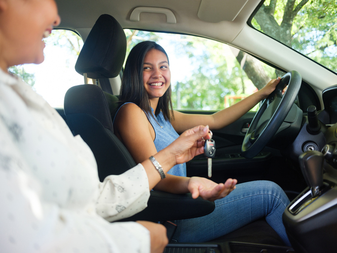 Mother handing daughter a car key
