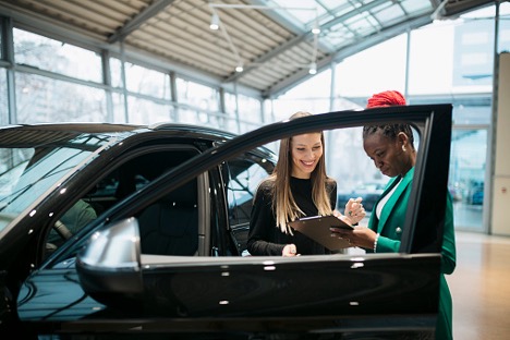 Two women looking at a clipboard at a dealership